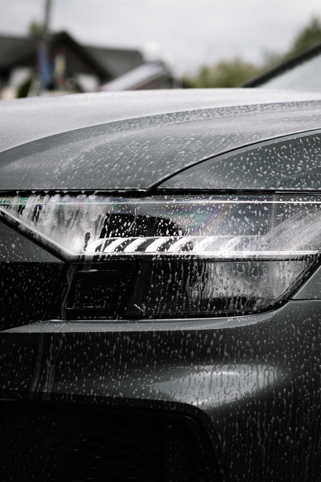 vertical shot of soap on a black shiny modern car at daytime